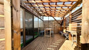 Eine Holzterrasse mit Pergola, Tisch und Stühlen.