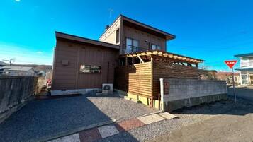 A building with a flat roof, a wooden structure on the ground level, and a clear sky.