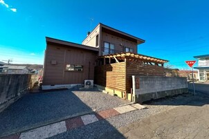 A building with a flat roof, a wooden structure on the ground level, and a clear sky.