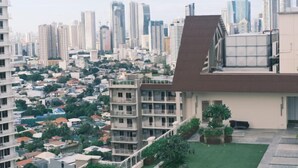 Un edificio de gran altura con un diseño moderno, que cuenta con varios balcones y un jardín en la azotea.