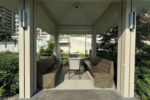 A covered outdoor seating area with benches and a table, surrounded by greenery. - TreehouseRiddle (Pasig)