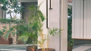 Un espacio exterior moderno con pared de piedra, plantas en macetas y piso a cuadros.