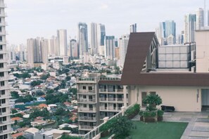 A residential area with high-rise buildings and a flat-roofed structure with a small garden. - TreehouseRiddle (Pasig)