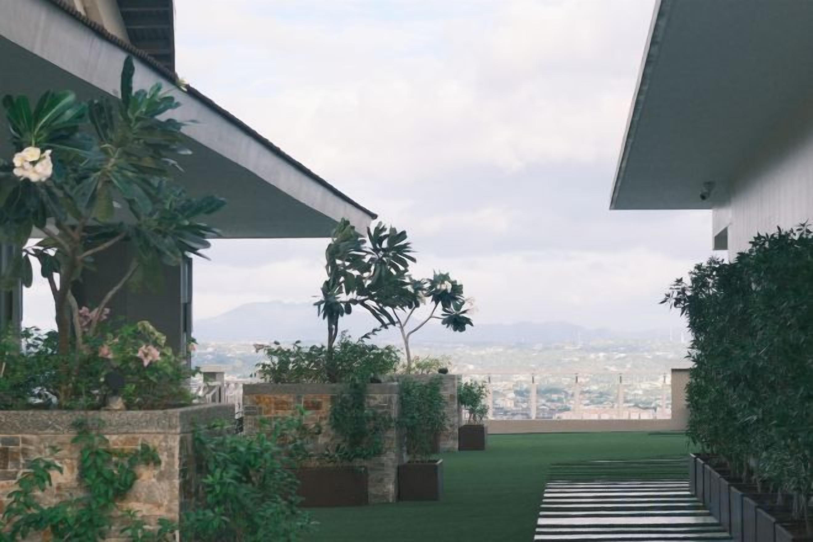 A modern building with a covered outdoor area featuring a green lawn and potted plants.