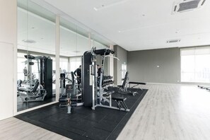 A gym with exercise equipment, large windows, and a wooden floor. - TR Residence BY FEEL HOME (Kuala Lumpur)
