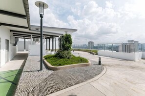 A rooftop terrace with a modern design, including a planter with greenery, a street lamp, and a clear view of the city skyline.