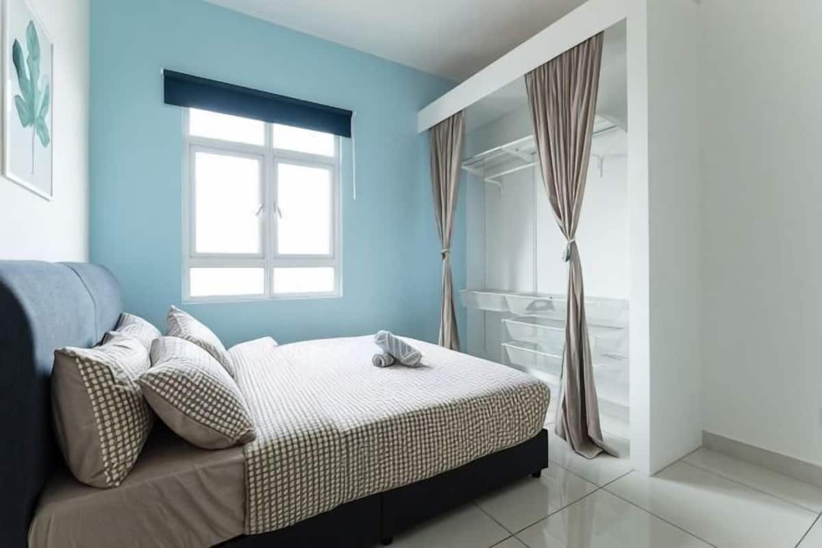 A bedroom with a bed, a window, curtains, and a view of the outside.