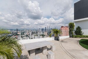 An outdoor terrace with a city view, a concrete table, and potted plants. - TR Residence BY FEEL HOME (Kuala Lumpur)