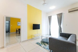 A living room with a sofa, a TV, and a dining area with chairs and a table. - TR Residence BY FEEL HOME (Kuala Lumpur)