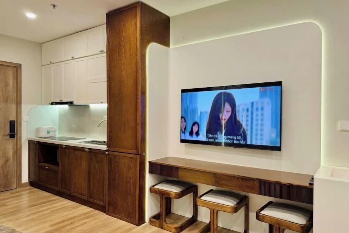 Una cocina moderna con armarios de madera, un lavamanos integrado y un televisor de pantalla plana montado en la pared.