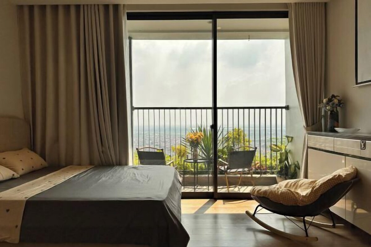 Une chambre avec un lit, une chaise, un balcon avec vue et un coin cuisine.