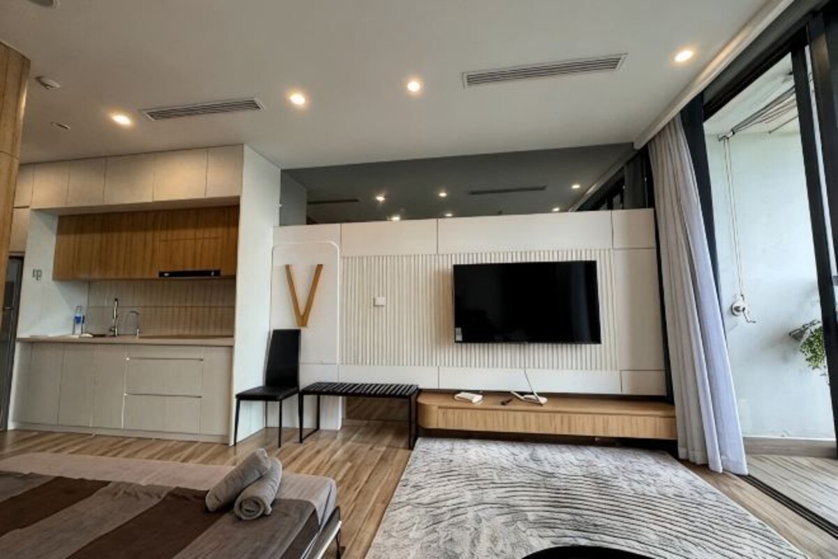 Un espacio habitable moderno con cocina, un televisor de pantalla plana en la pared, un sofá y un ventanal grande.