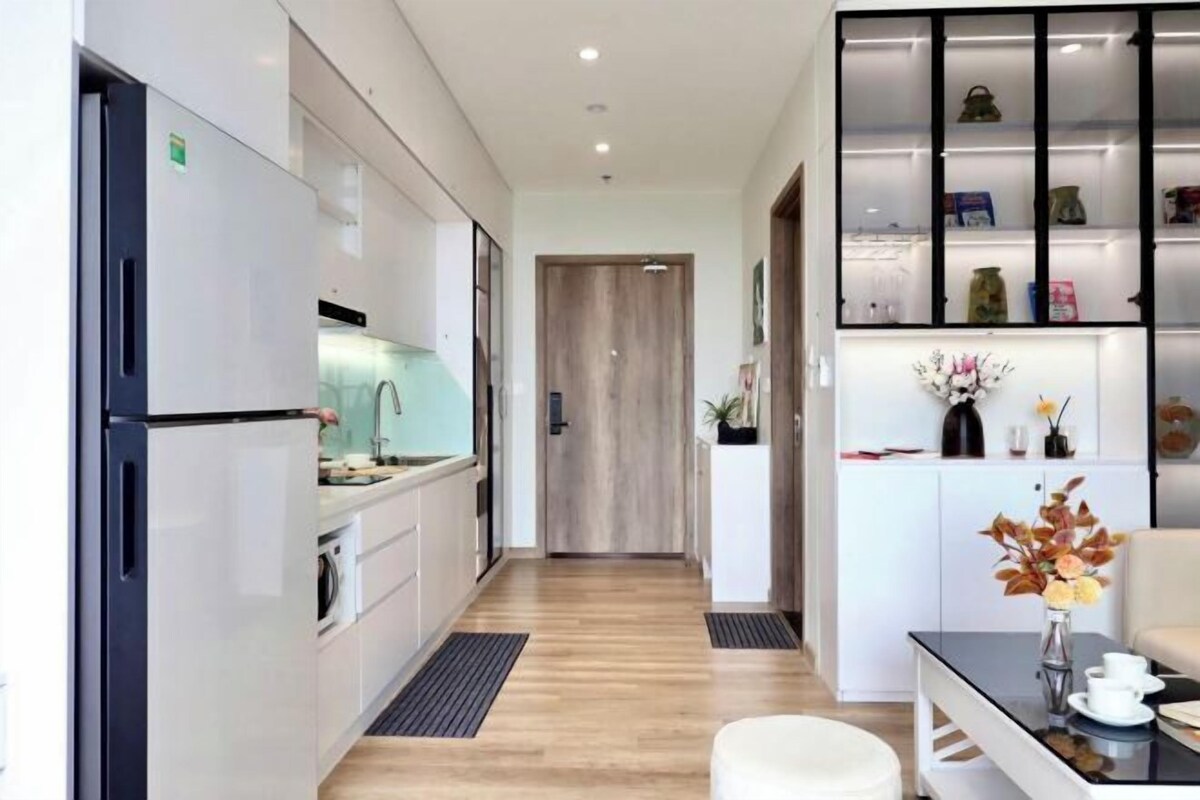 Une cuisine moderne avec des meubles blancs, un réfrigérateur noir et un plancher en bois.