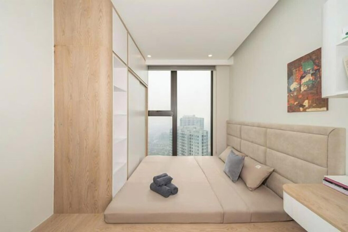 A modern bedroom with a bed, a window, and a painting on the wall.