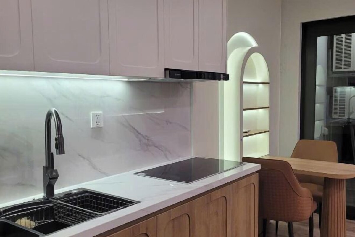 A modern kitchen with a built-in stove, a sink, and wooden cabinets.