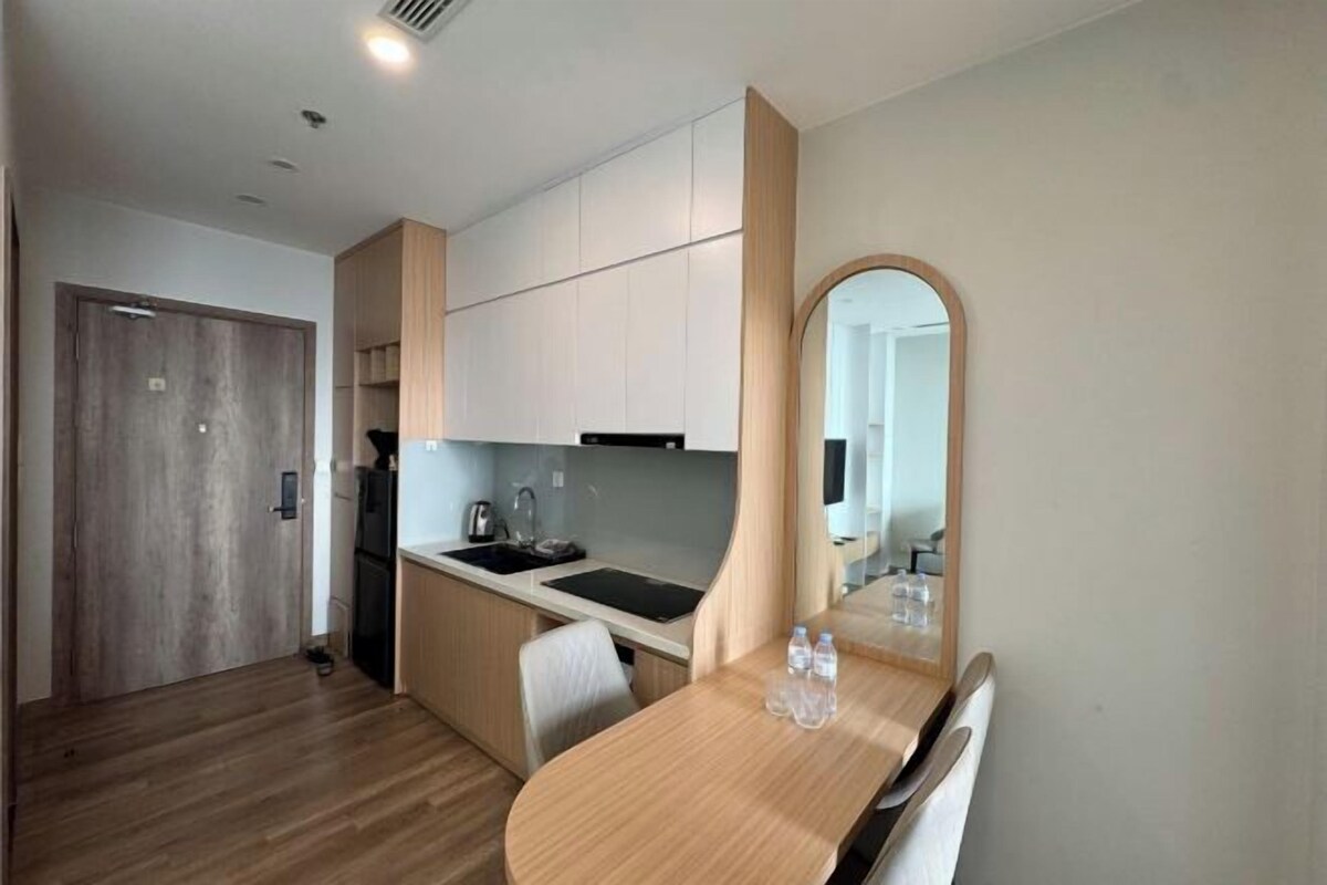 A compact kitchen with a wooden dining table, a built-in oven, and a microwave.