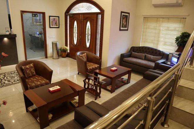 A spacious living area with a sofa, armchairs, and a coffee table. A staircase with a metal railing is visible in the background.