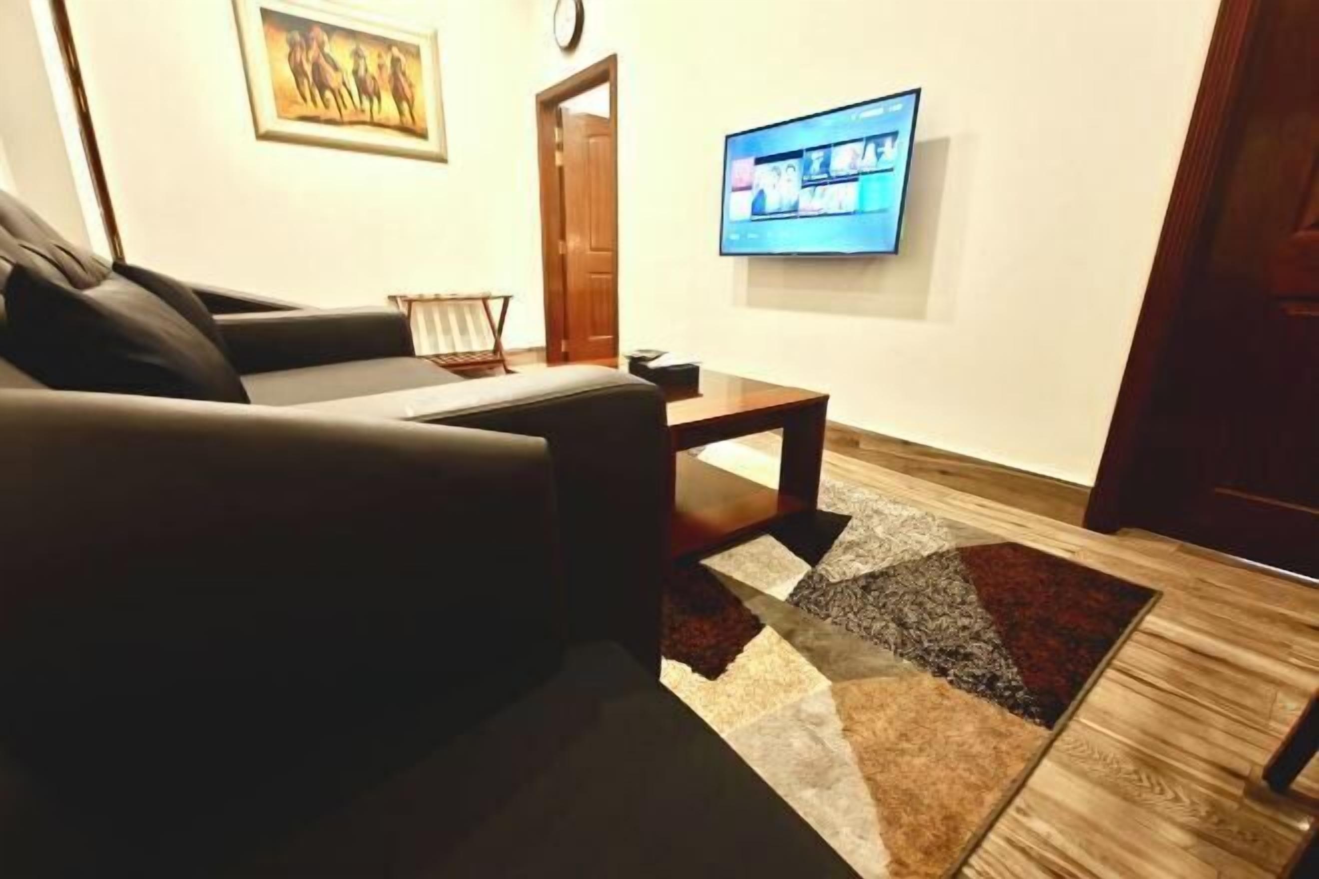 A living room with a sofa, a coffee table, a rug, a TV, and a door.