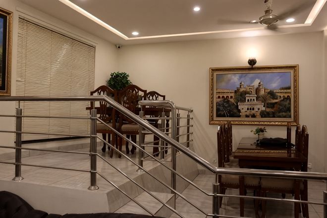 A staircase leading to a dining area with a table and chairs, a framed picture on the wall, and a ceiling fan.