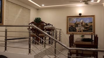 A staircase leading to a dining area with a table and chairs, a framed picture on the wall, and a ceiling fan.