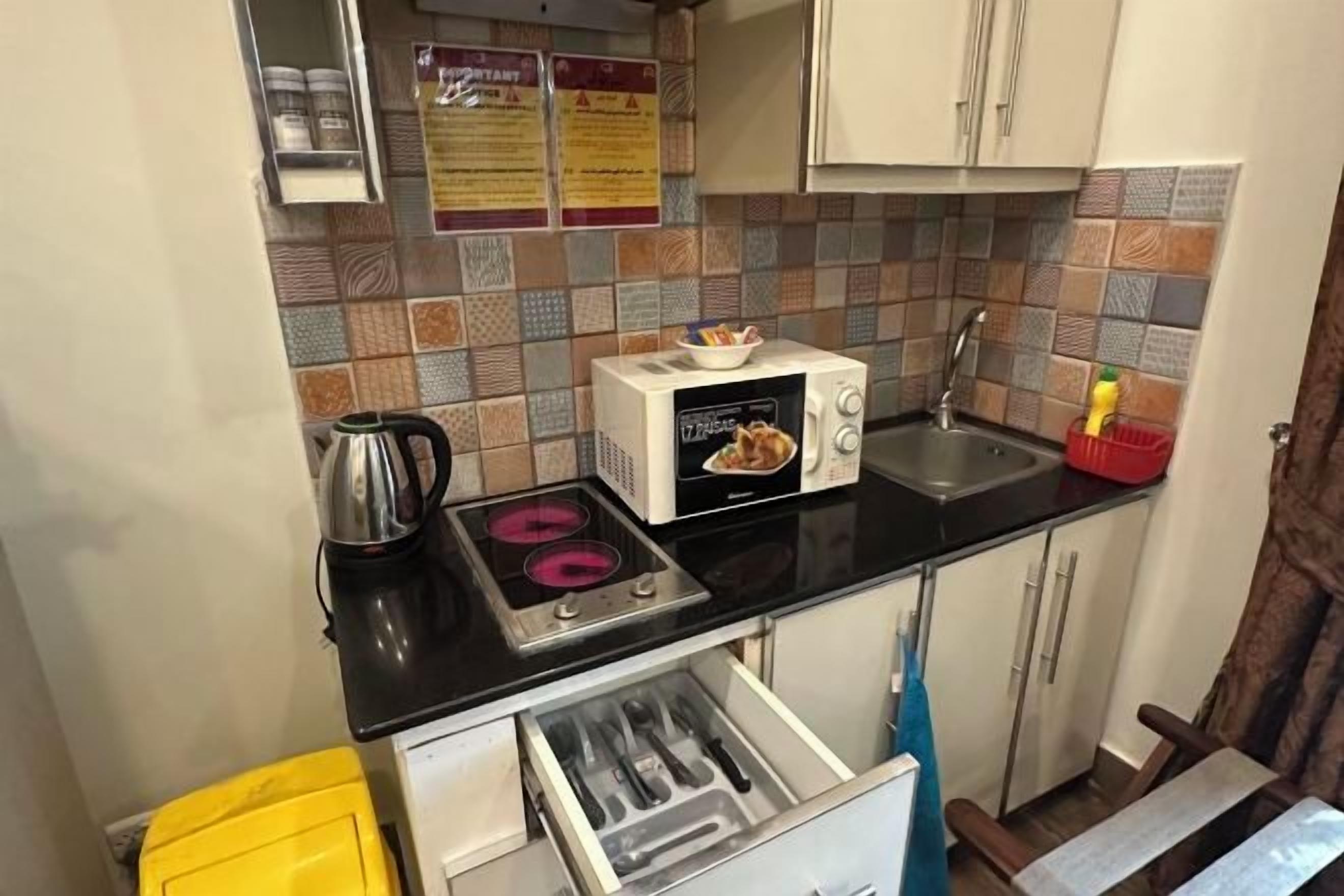 Una cocina compacta con estufa a gas, microondas, pileta y un mueble pequeño.