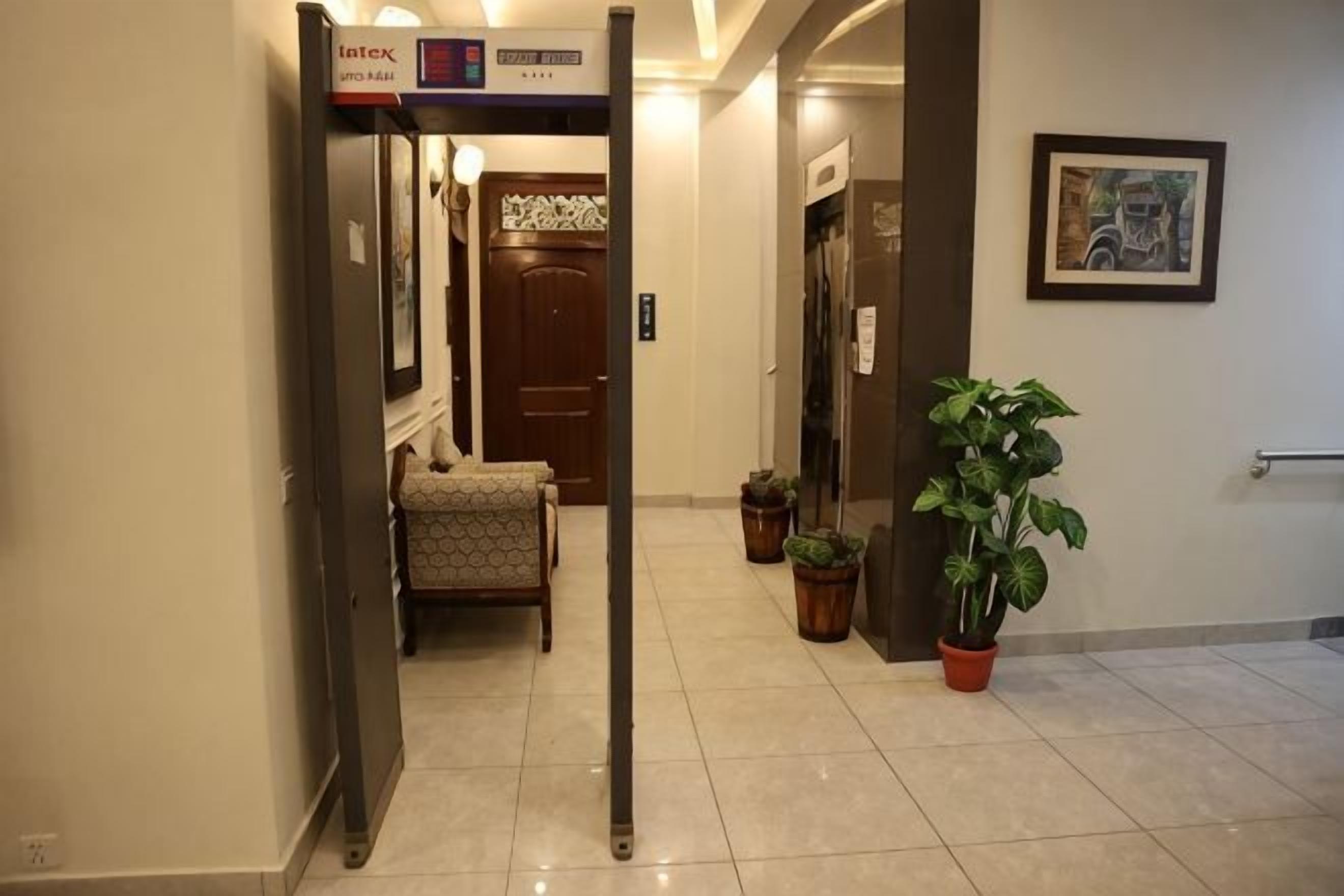 A hotel hallway with a reception desk, a door, and a potted plant.