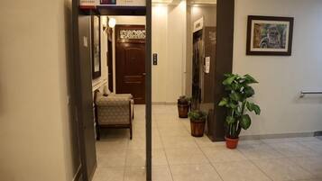 Pasillo de hotel con mostrador de recepción, una puerta y una planta en maceta.