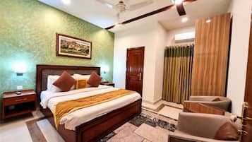 A bedroom with a bed, nightstands, a chair, a ceiling fan, a door, and curtains.