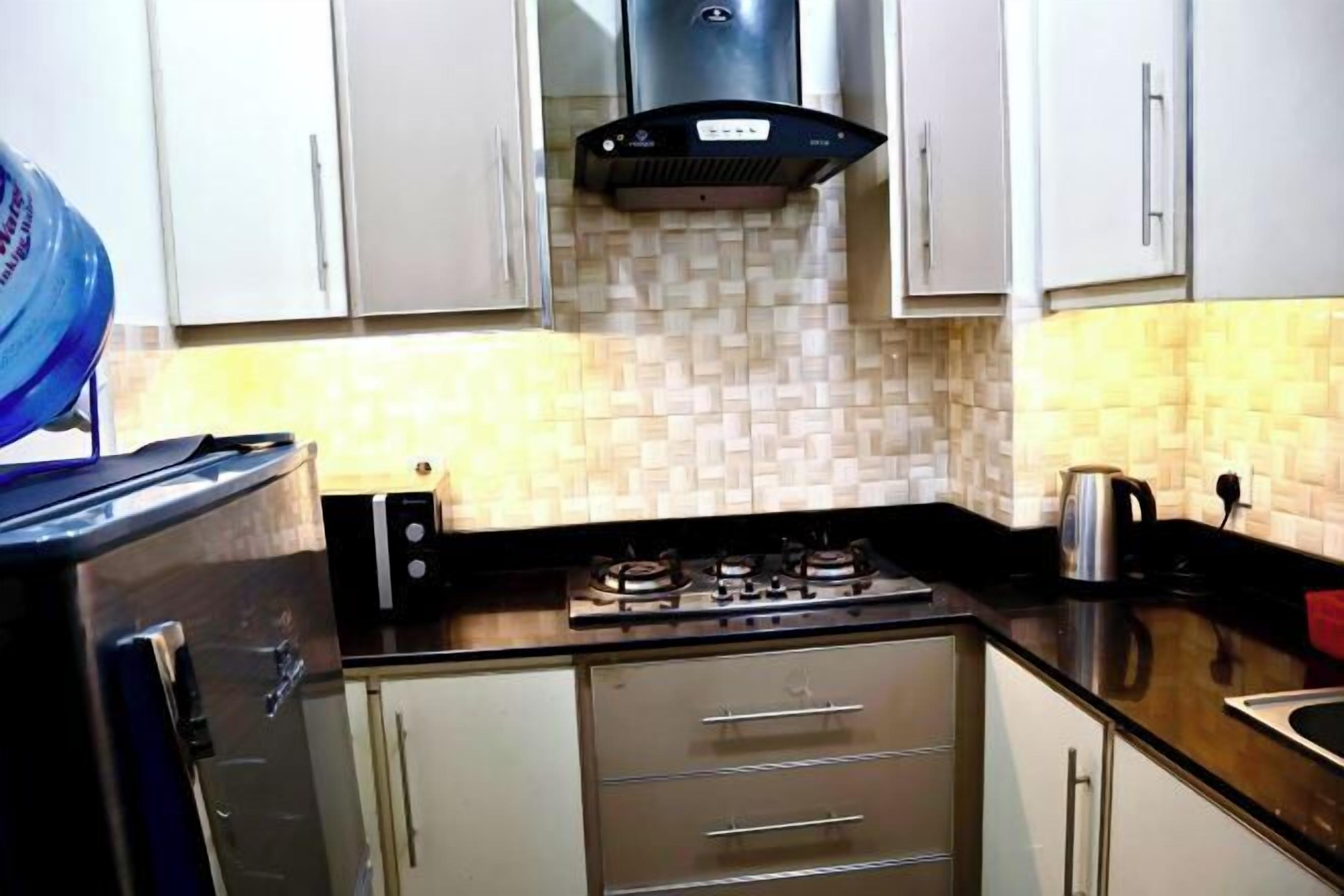 A kitchen with white cabinets, a gas stove, a kettle, and a water dispenser.
