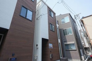 A multi-story residential building with a brown exterior, a visible entrance, and a sign indicating a rental property. - Four Seasons Yado 1 (Tokyo)