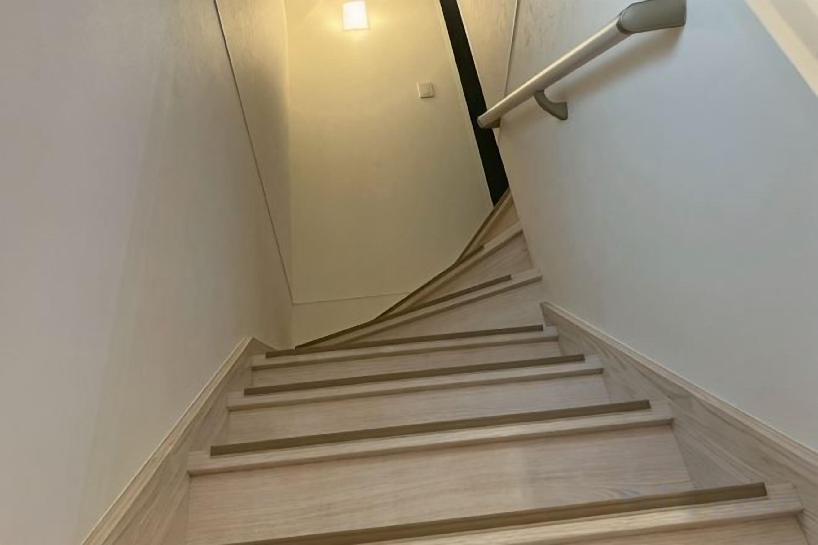 A wooden staircase with a handrail, leading to a door at the top.