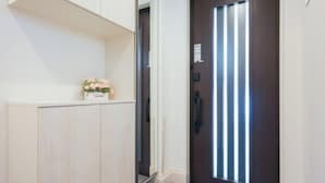 A hallway with a dark wooden door, a white cabinet, and a small floral arrangement on the cabinet. - Four Seasons Yado 1 (Tokyo)