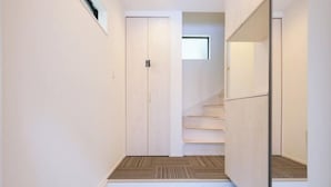 A hallway with a wooden floor, a white door, and a staircase with wooden steps. - Four Seasons Yado 1 (Tokyo)