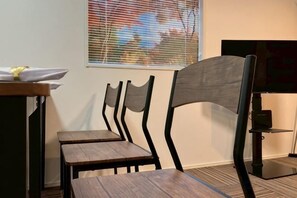 A room with a wooden table, two chairs, a television, and a window with blinds. - Four Seasons Yado 1 (Tokyo)