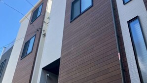 A multi-story building with a modern architectural design, featuring a combination of white and brown exterior panels and multiple windows. - Four Seasons Yado 1 (Tokyo)