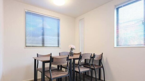 A dining area with a table and chairs, a window with blinds, and a patterned carpet. - Four Seasons Yado 1 (Tokyo)
