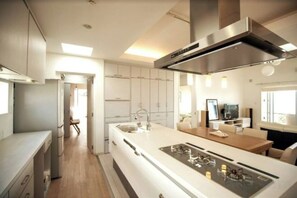 Cozinha moderna com ilha central, eletrodomésticos de aço inoxidável e vista para a área de refeições.