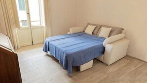 A bedroom with a bed, a sofa, a wooden floor, and a window. - Modern apartments in the heart of Florence (Florence)