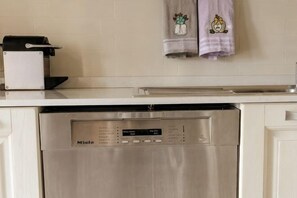 Eine Küche mit einem Edelstahl-Geschirrspüler, einem Toaster und zwei Handtüchern, die an der Wand hängen.