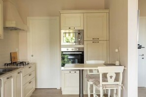 A compact kitchen with white cabinetry, a built-in oven, and a small dining area with a white table and chair. - Modern apartments in the heart of Florence (Florence)
