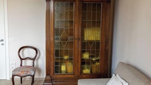 A room with a wooden cabinet with glass doors, a floral-patterned chair, and a sofa. - Modern apartments in the heart of Florence (Florence)