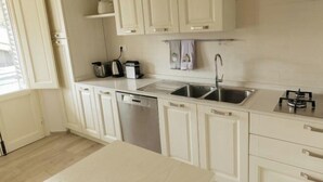 A modern kitchen with white cabinetry, a dishwasher, a sink, and a gas stove. - Modern apartments in the heart of Florence (Florence)
