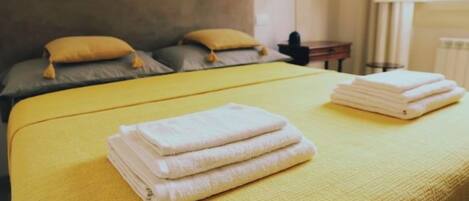 Una cama con un edredón amarillo y dos toallas blancas dobladas con cuidado.