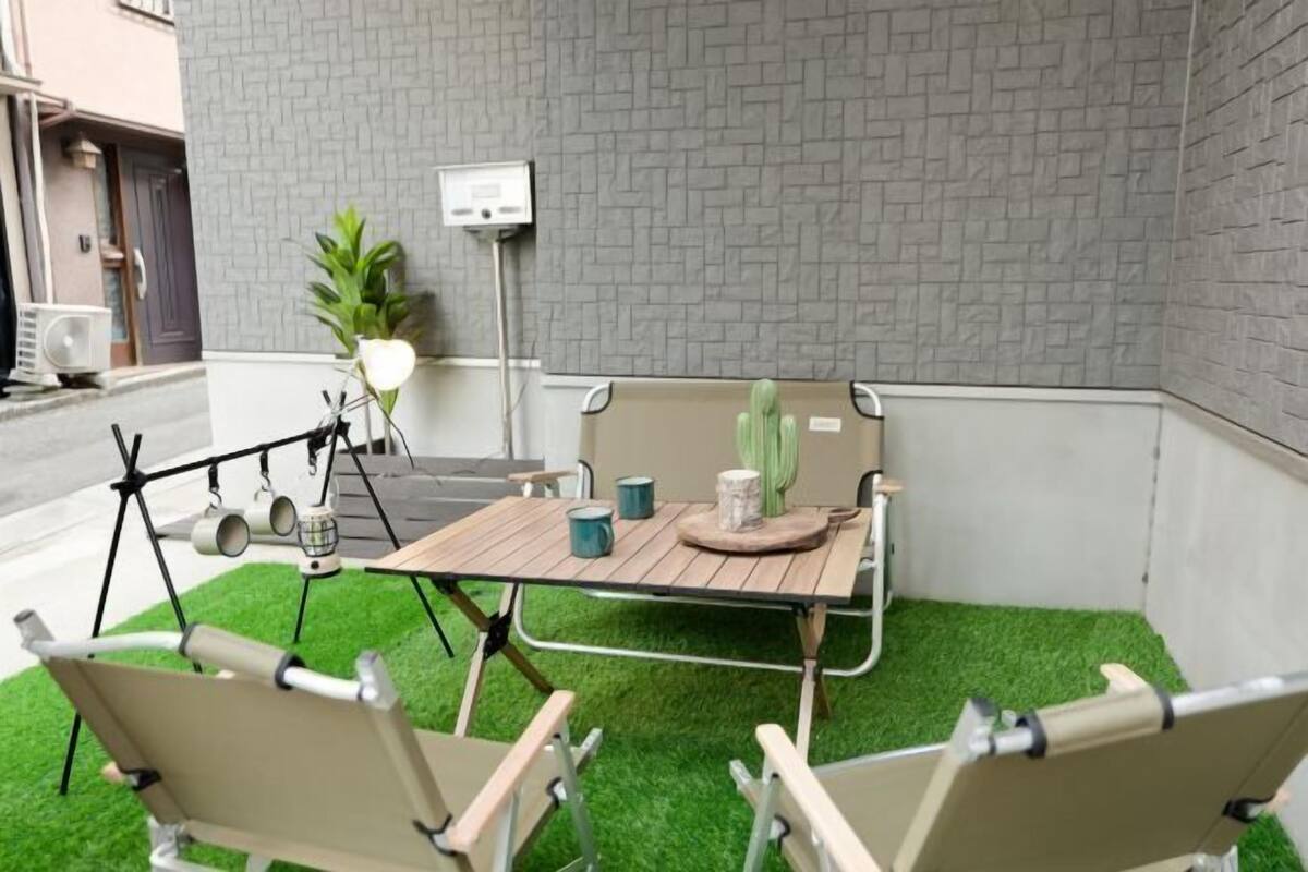 A patio with a table and chairs, a cactus, and a wall-mounted device.