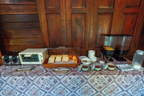 A breakfast setup with a toaster, a tray of bread, and various condiments on a patterned tablecloth. - Himdoihome Maekampong (Mae On)