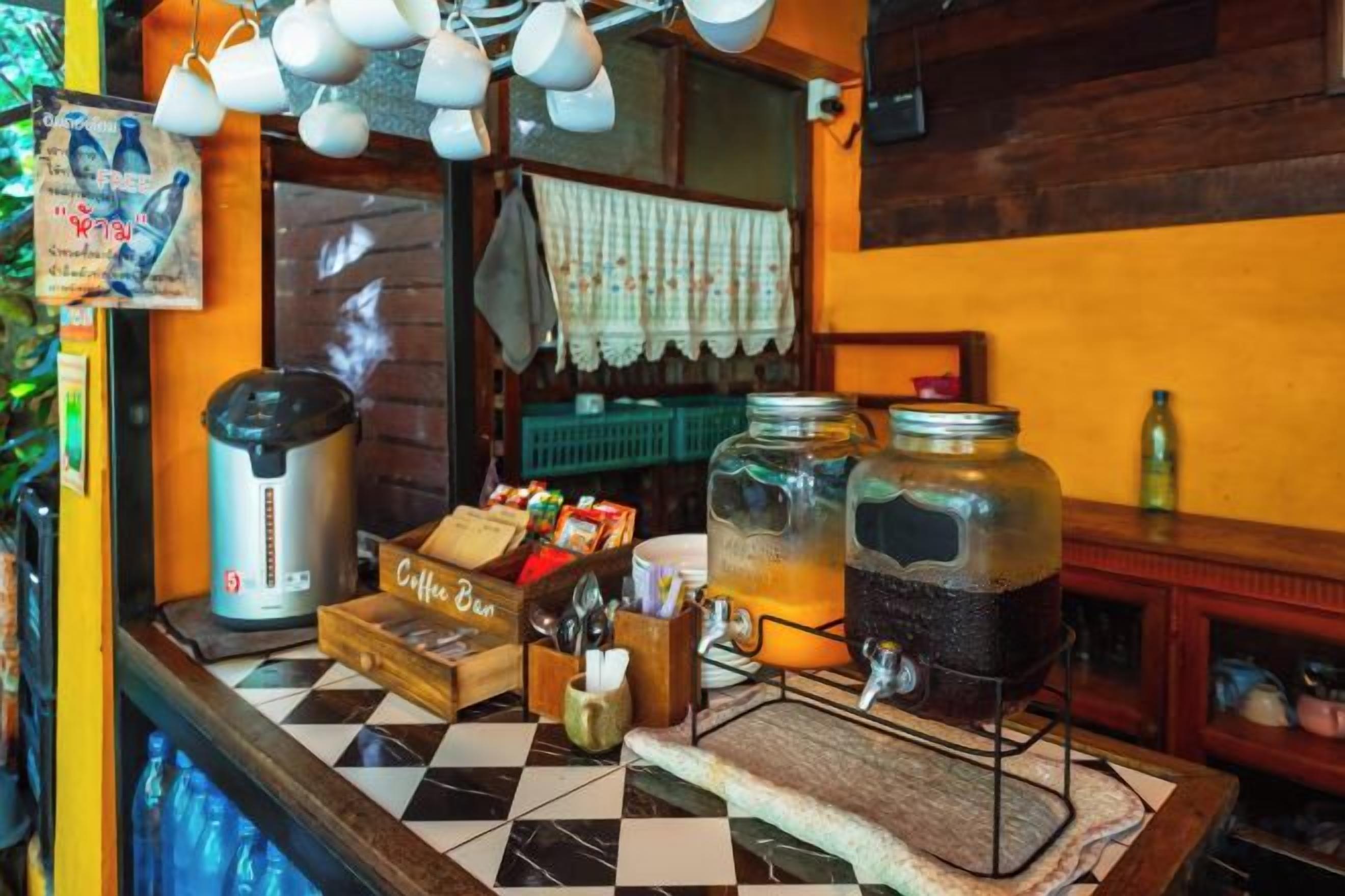 A coffee station with a coffee machine, jars of coffee, and a checkered tablecloth.