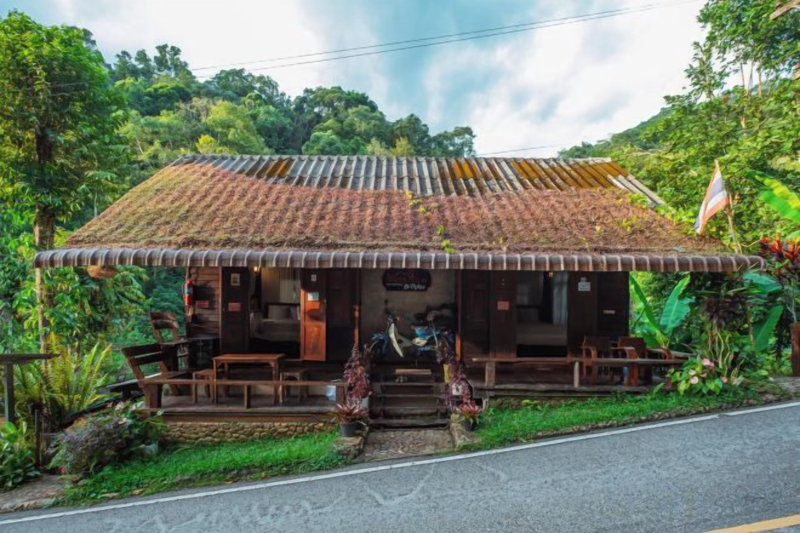 A rustic building with a tiled roof, wooden porch, and steps leading to the entrance.