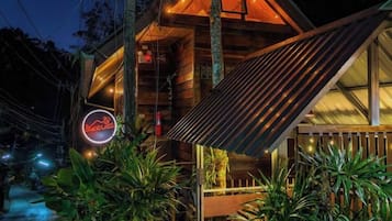 Een modern gebouw met een schuin dak, een neonbord en een houten terras.