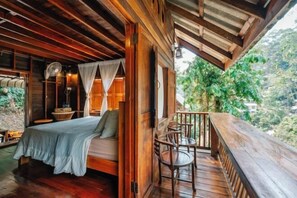 Una habitación de madera con cama, un ventilador y un balcón con vistas a la vegetación.