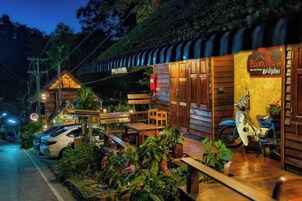 A wooden building with a sign that reads 'Drinks' and a motorcycle parked outside.